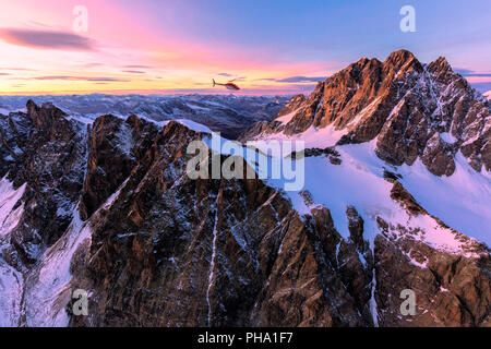 Luftaufnahme der Hubschrauber im Flug in Richtung Piz Roseg bei Sonnenuntergang, Berninagruppe, Grenze zwischen Italien und der Schweiz, in Europa Stockfoto