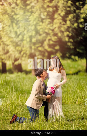 Zukunft Papa kniend zu erwarten Mama mit Blumen in der Hand Stockfoto