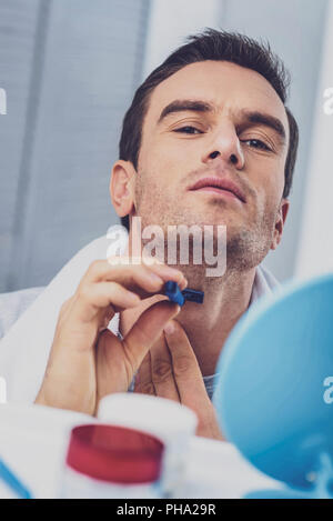 Mann rasieren Gesicht gewissenhaft stehend im Bad Stockfoto