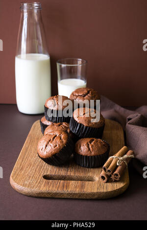 Hausgemachte Schokolade Muffins (Brownies) mit Zimt und Milch auf braunem Papier Hintergrund Stockfoto