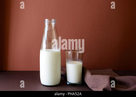 Flasche Milch und Milch Glas auf braunem Papier Hintergrund. Gesunde Ernährung Konzept Stockfoto