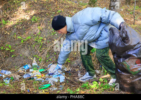 Junger Mann sammelt Müll im Wald Stockfoto