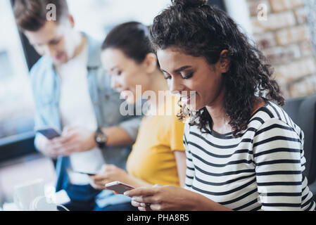 Optimistisch drei Freunde Verfassen von Nachrichten Stockfoto
