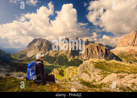 In der wunderschönen alpinen Landschaft eingebettet, ein Mann bewundert die hochalpine Landschaft mit Bergen und bewölktem Himmel. Stockfoto