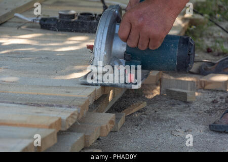 Elektrische Kreissäge wird ein Stück Holz von Carpenter schnitt. Details der Konstruktion der männlichen Arbeiter. Schalung für den Zaun. Stockfoto