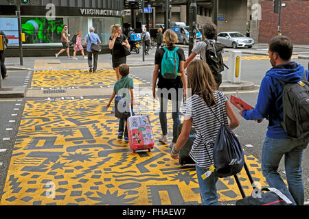 Familie mit Gepäck auf Eley Kishimoto Kunst' farbenfrohe Kreuzungen" Buche Street Tunnel & Barbican Station, Kulturmeile, Stadt London UK KATHY DEWITT Stockfoto
