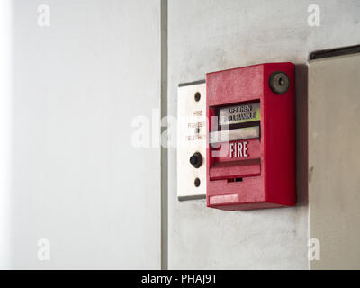 Drucktaster, Feueralarm an graue Wand für Alarm- und Sicherheitssystem mit Feuerlöscher Port. Stockfoto