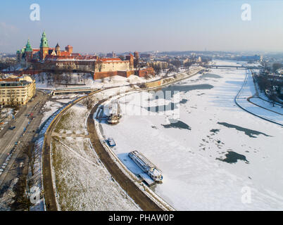 Krakau, Polen, im Winter. Schloss Wawel, der Kathedrale und teilweise gefrorene Weichsel mit Hafen, Schiffe und Grunwaldzki Brücke. Luftaufnahme. Stockfoto