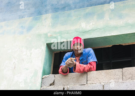 Havanna, Kuba/März 22, 2016: Afro-kubanischer Arbeiter, Tragen von Uniformen, blickt Fenster von Gebäude im Bau. Stockfoto