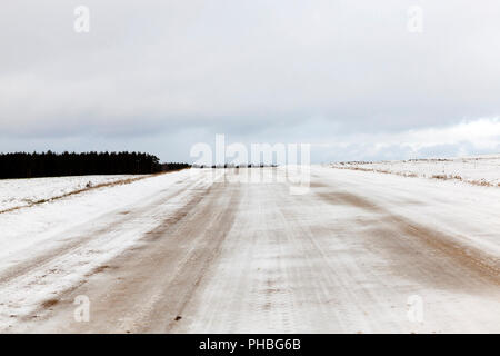 Straße auf dem schmutzigen Schnee gelber Farbe von Sand und Schmutz nach der Behandlung von der Straße Stockfoto