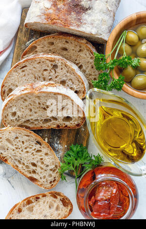 Hausgemachtes Brot mit Oliven, sonnengetrockneten Tomaten und Olivenöl. Stockfoto