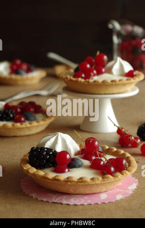 Kleine Törtchen mit Vanillecreme, Beeren und meringue Stockfoto