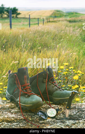 Wanderschuhe mit Messer und Kompass auf Log in Feld Stockfoto