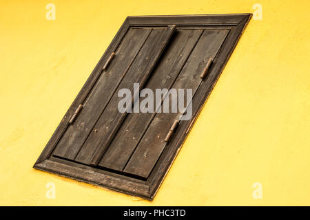 Gelbe Wand mit Holz braun Fenster. Abstrakte Komposition Stockfoto