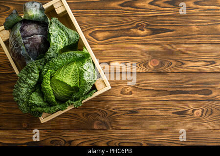 Zwei Köpfe von frischen Rotkohl und Wirsing zusammen in eine kleine Holzkiste auf eine Tabelle mit Kopie Raum Holztisch auf eine organische Farmers Market i Stockfoto