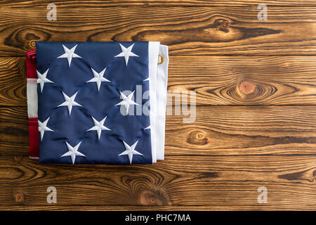 Akkurat gefaltete Amerikanische Flagge zeigen die Stars, die für die ursprünglichen 13 Kolonien auf einem holztisch von Overhead mit Kopie Raum gesehen Stockfoto