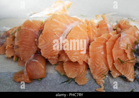 In Scheiben geschnitten gesalzen Lachsfilet auf Papier Stockfoto