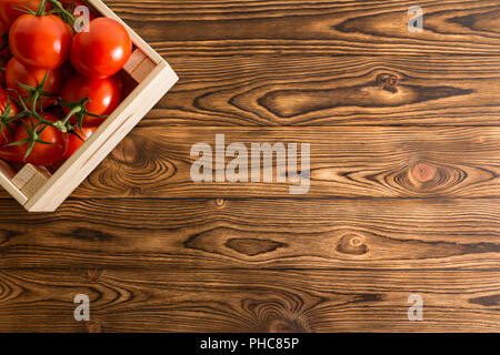 Saftige reife rote Bio Tomaten in einem Verschlag in der Ecke auf einem rustikalen Holztisch am Bauernmarkt mit Kopie Raum gesehen von oben Stockfoto