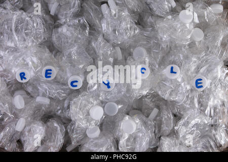 Kunststoff PET Flaschen zerkleinert für das Recycling in einem full frame Hintergrund Textur mit einer Reihe von Flaschen mit ihren weißen Kappen und die handschriftlichen Text-Re Stockfoto