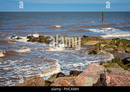 Wellen wirbeln um die Felsen an der Küste bei Rossall, Fylde Coast, Lancashire Stockfoto