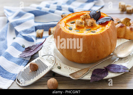 Kürbissuppe mit Gewürzen und Croutons im Kürbis. Stockfoto