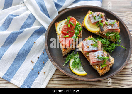 Gegrilltes Brot mit Chunks von Hering, Kaviar und Schnittlauch. Stockfoto