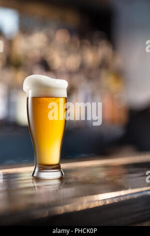 Glas helles Bier in einer dunklen Kneipe Stockfoto
