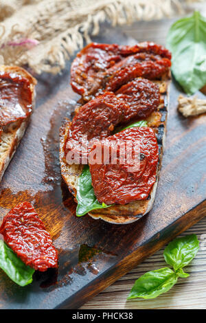 Bruschetta mit getrockneten Tomaten und Basilikum. Stockfoto