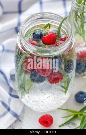 Eis glitzernden Wasser, Beeren und Estragon in jar. Stockfoto