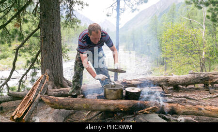 Die touristische stört eine Suppe, die Soße in einem Topf auf einem ksotra in der Wanderung. Stockfoto