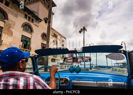 Havanna, Kuba/März 22, 2016: Kubanische mann Laufwerke blue Vintage convertible Taxi unter grauem Himmel durch die Straßen mit kolonialer Architektur, gesäumt. Stockfoto