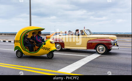 Havanna, Kuba/März 21, 2016: Drei Taxis auf dem Malecon Highway, einer ist ein Vintage convertible und ein anderes Mini Moto coco Taxi. Stockfoto