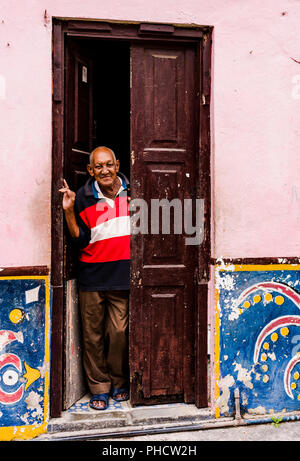 Ältere kubanischen Mann sieht sich durch offene Tür von Haus im Kolonialstil in Havanna, Kuba. Stockfoto