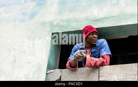 Kubanische Bauarbeiter nimmt einen Bruch aus dem Fenster in die Altstadt von Havanna, Kuba zu blicken. Stockfoto