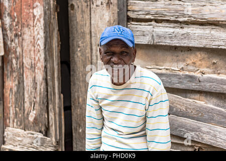 Portrait eines älteren Afro Mann gegen eine reich strukturierte Hintergrund einer weatherbeaten Holzhaus. Er zeigt seine Unterstützung für die NY Yankees. Stockfoto