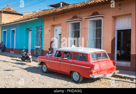 Trinidad, Kuba / 15. März 2016: Leuchtend roter Vintage-Kombi, der auf der Kopfsteinpflasterstraße der UNESCO-Weltkulturerbestadt Trinidad, Kuba, geparkt ist. Stockfoto