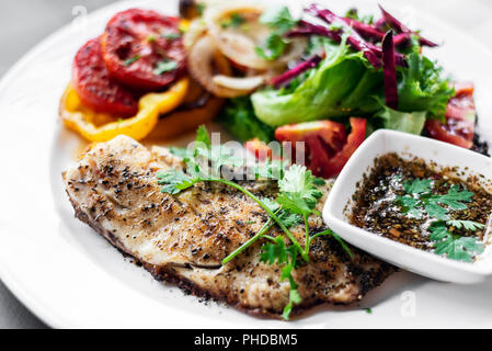 Tilapia Fischfilet mit gemischter Salat gegrilltes Gemüse und Kräuter-Vinaigrette Sauce Stockfoto