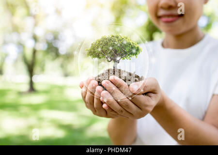 Welt und Innovation Konzept Sparen, Mädchen, dass kleine Pflanze oder Baum Bäumchen Wachsen aus dem Boden auf dem Palm mit Anschlussleitung und Handschuh. Stockfoto