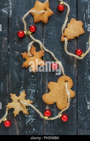 Weihnachtsgirlande aus Lebkuchen und roten Kugeln. Stockfoto