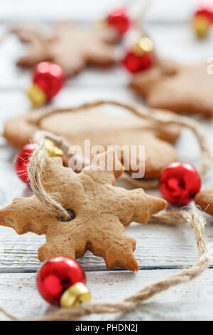 Die Girlande aus Weihnachtsplätzchen und roten Kugeln. Stockfoto