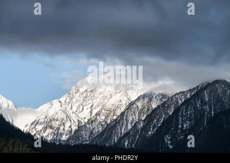 Die schneebedeckten Berge und misty Wolken Stockfoto