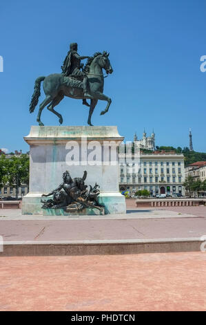 Reiterstandbild Ludwigs XIV. auf dem Place Bellecour mit der Basilika Notre-Dame de Fourvière im Hintergrund auf dem Hügel, in Lyon, Frankreich. Stockfoto