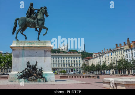 Reiterstandbild Ludwigs XIV. auf dem Place Bellecour mit der Basilika Notre-Dame de Fourvière im Hintergrund auf dem Hügel, in Lyon, Frankreich. Stockfoto