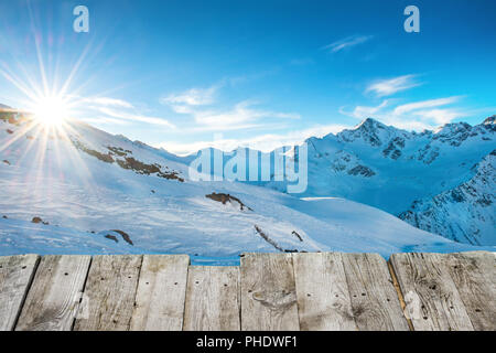 Blick vom hölzernen Tisch bis zum Sonnenuntergang in den Bergen Stockfoto