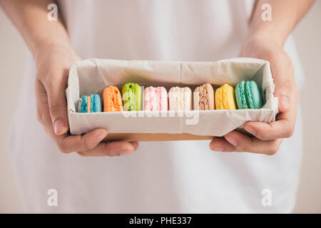 Hände, die farbenfrohen Pastelltönen Kuchen macarons oder Makronen Stockfoto