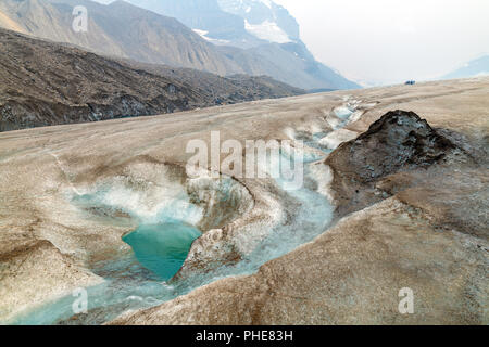 Oberflächenwasser durch gewundene Kanal auf dem Athabasca Gletscher schmelzen fließt. Es gibt einige Leute im Hintergrund die Erkundung der Gletscher zu Fuß Stockfoto