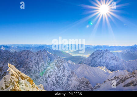 Ein Blick ins Tal vom höchsten Punkt Deutschlands, der Zugspitze. Der Blick geht über sterben sonnenbestrahlte Winterlandschaft im Wettersteingebirge. Stockfoto