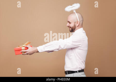 Profil Seitenansicht glücklich aussehenden im mittleren Alter kahl bärtige Engel in Hemd und weißem Heiligenschein auf dem Kopf stehend und roten Geschenk mit toothy Lächeln. stu Stockfoto