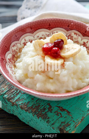 Milch Reisbrei mit Bananen, Beeren und Honig. Stockfoto