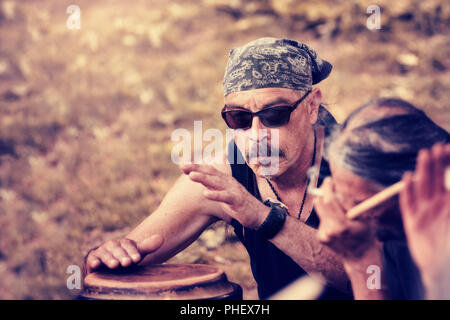 Cool Latino mittleren alter Mann mit einem Taschentuch spielt Rhythmus mit Djembe bongo bei einer indigenen Ritus in Montreal, Quebec, Kanada drum. Stockfoto